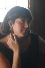 Load image into Gallery viewer, woman in a dark dress in a dimly lit barn with light filtering through the window. wearing bronze spiral stud earrings and bronze rings. 
